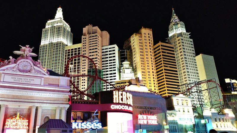 a city at night with tall buildings and a carousel